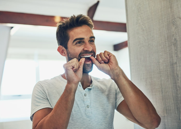 man flossing his teeth